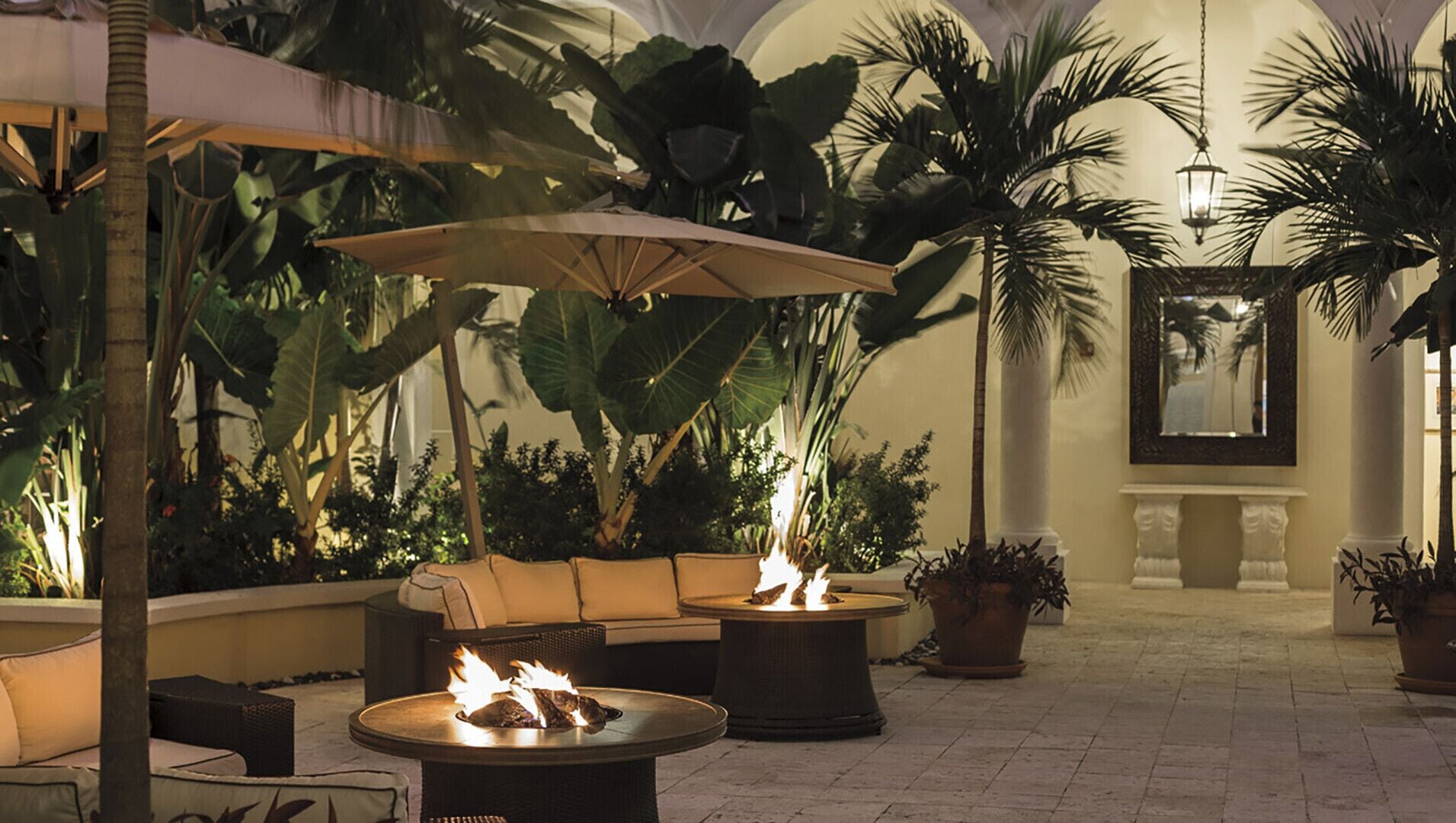 A cozy outdoor seating area with a fire pit, lounge chairs, and large umbrellas.