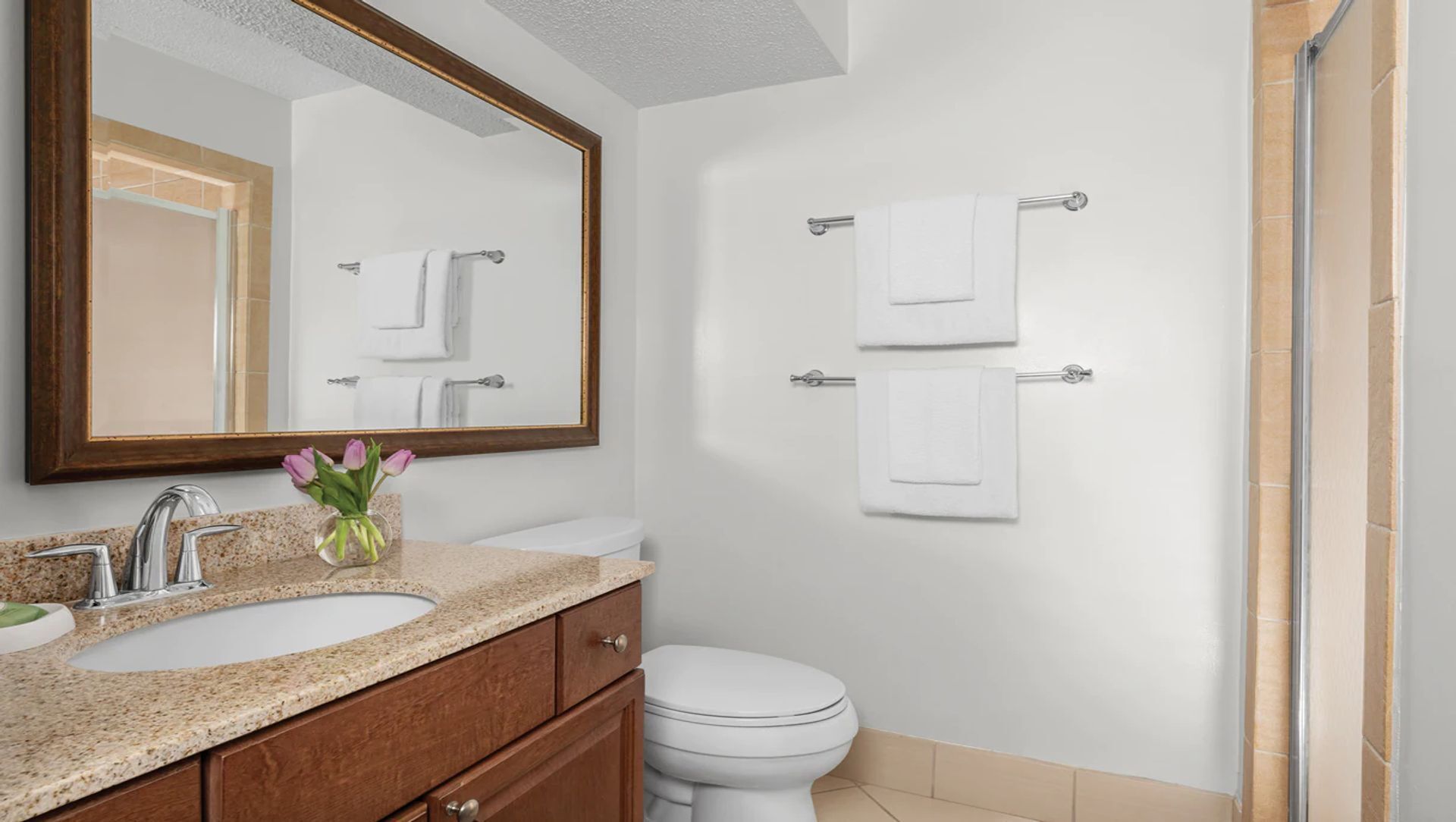 Un baño con lavamanos, espejo y dos toallas colgadas.