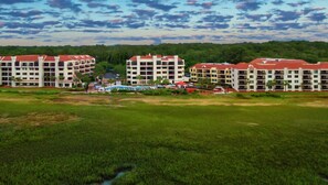 Ein Hotelkomplex mit mehreren Gebäuden, einem Schwimmbad und einer grünen Landschaft.