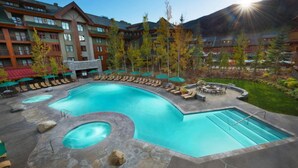 A resort pool with a circular hot tub, lounge chairs, and a stone deck.