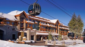Ein Skigebäude mit Seilbahn, Steinpfeilern und verschneiter Umgebung.