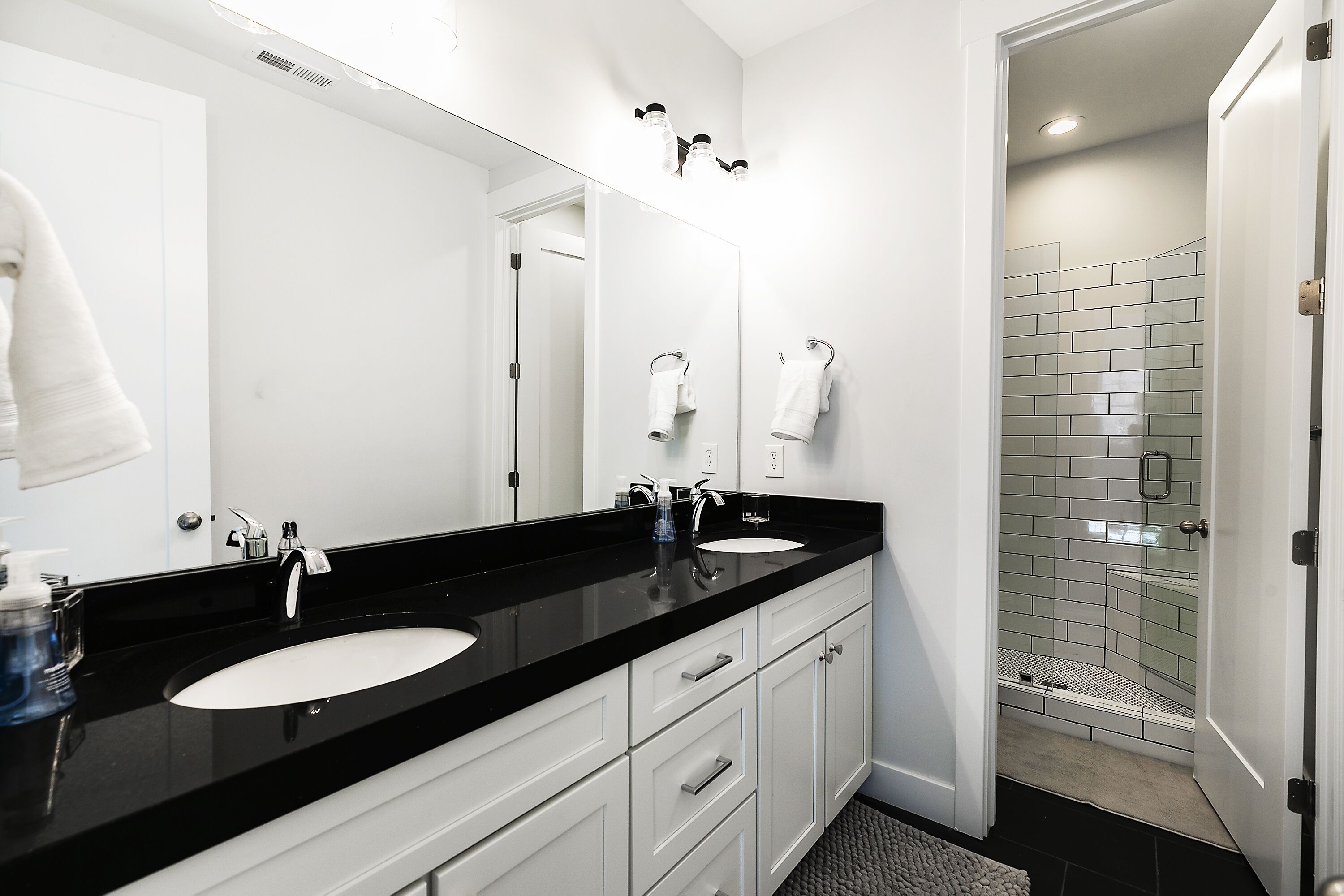 A bathroom with two sinks, a large mirror, and a glass shower enclosure.
