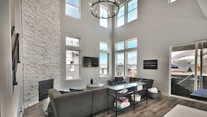 A spacious living area with a fireplace, a sofa, a coffee table, and a television. - Gorgeous Jordanelle Lake Property - 4BD/3.5BA (Hideout)