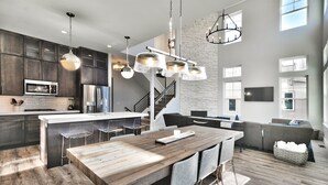 A modern kitchen with dark wood cabinets, a central island, and pendant lighting. - Gorgeous Jordanelle Lake Property - 4BD/3.5BA (Hideout)