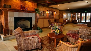 Un hall acogedor con muebles de mimbre, chimenea y un centro de mesa floral.