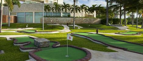 Un parcours de mini-golf avec neuf trous, entouré de pelouse bien entretenue et de palmiers.