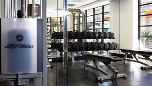 A gym with weightlifting equipment, a bench, and dumbbells.