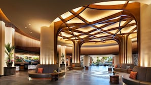 A spacious lobby with curved wooden beams, comfortable seating, and a large window offering a view of the outdoors.