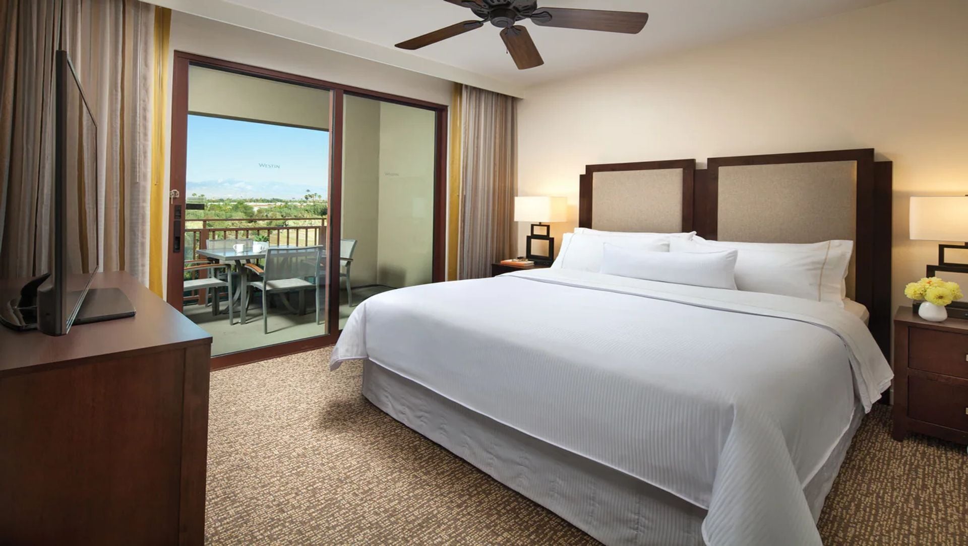 Habitación de hotel con una cama grande, un escritorio, una silla, una mesa y un balcón con vistas.