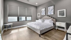 Un dormitorio con una cama grande, un ventilador de techo, una ventana con persianas y obras de arte en las paredes.