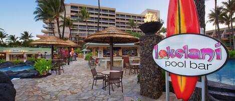 A pool bar area with outdoor seating, a sign for 'Lokelani pool bar', and a building in the background.