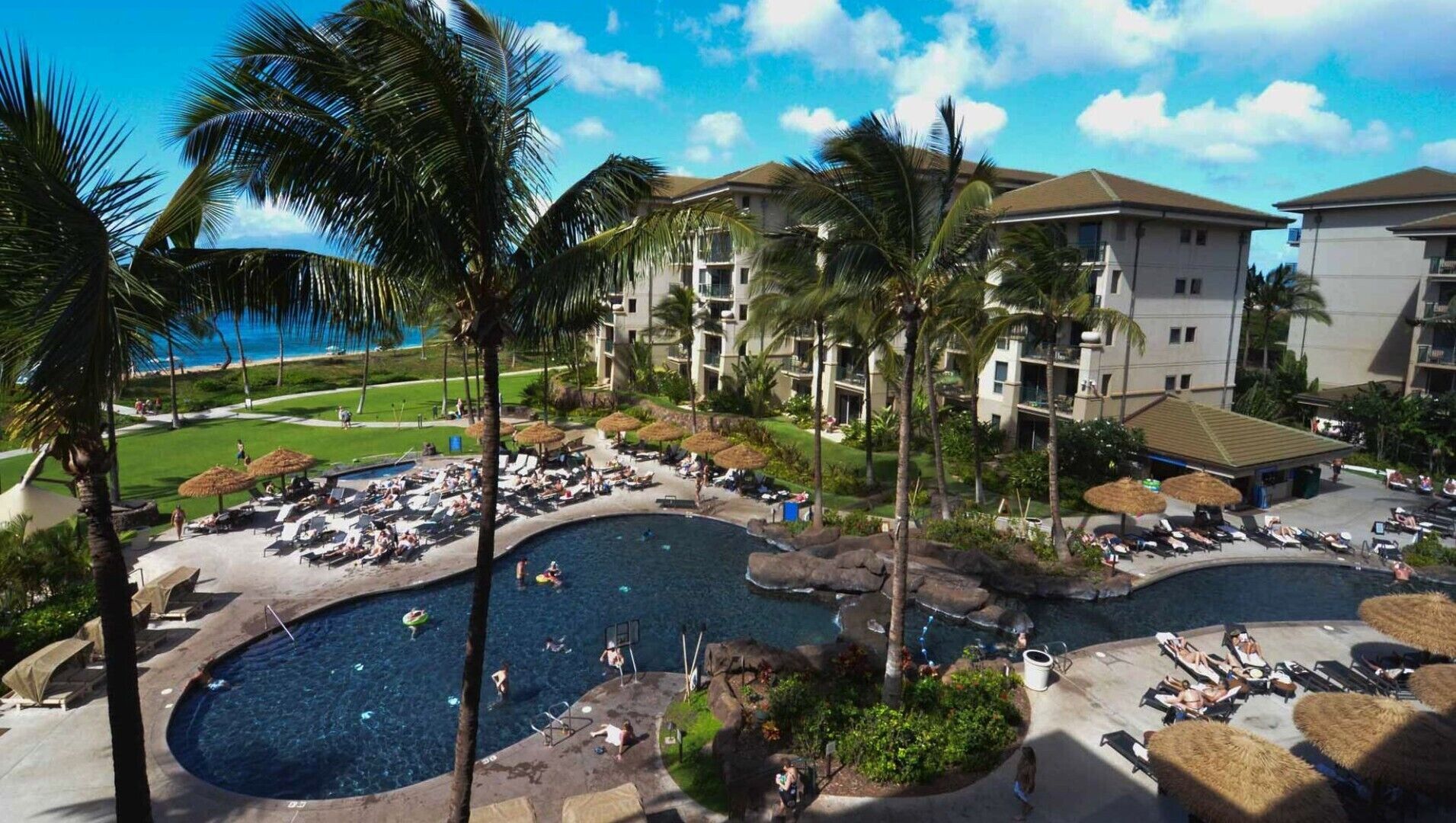 Ein Resort mit mehreren Schwimmbecken, Palmen und Blick auf den Ozean.