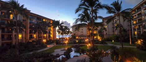 A resort with multiple-story buildings, a central courtyard with a water feature, and palm trees.