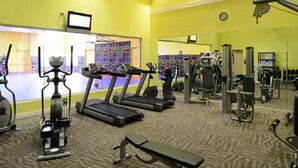 Un gimnasio con cintas de correr, elípticas y equipo de pesas.