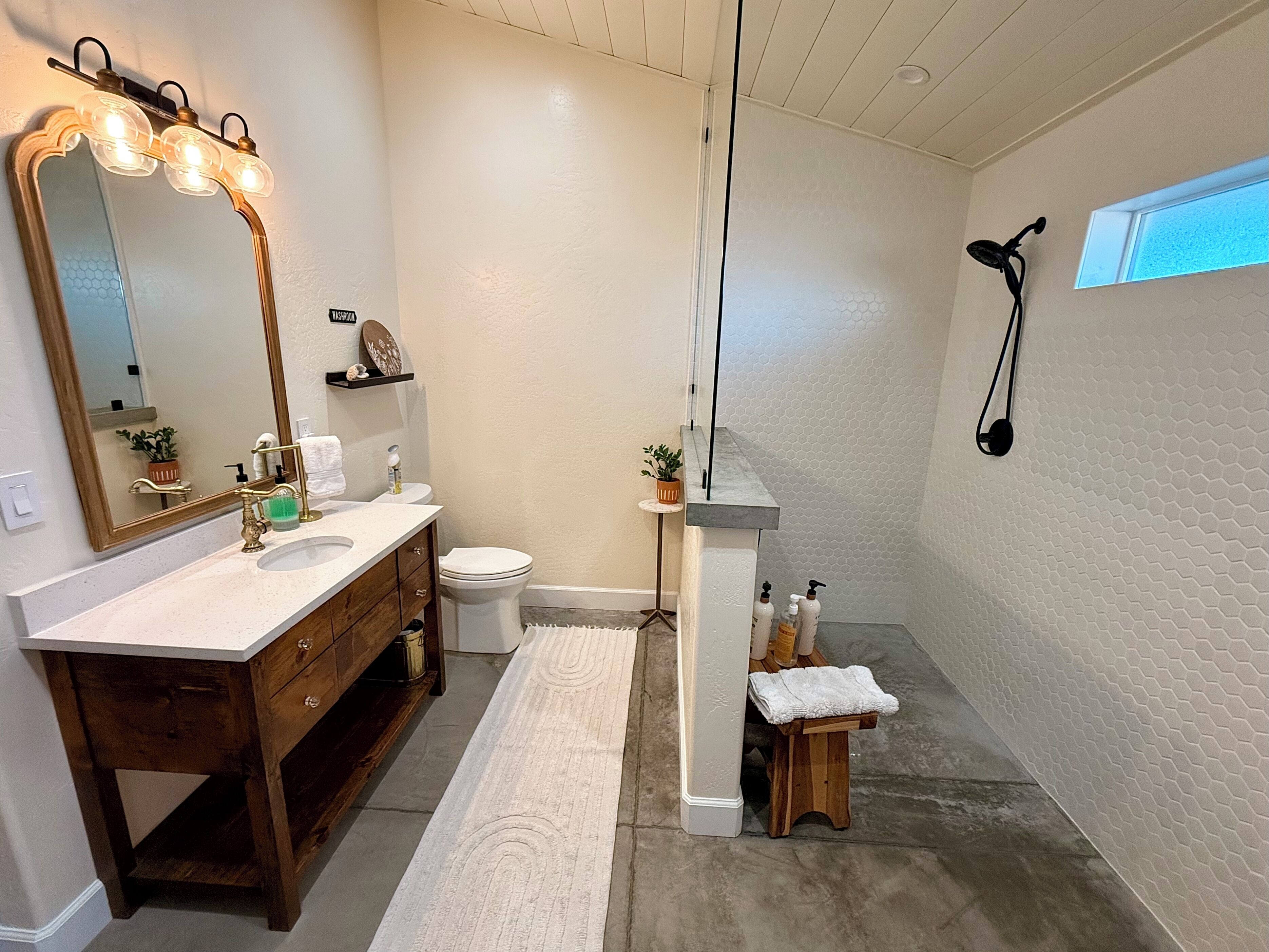 A bathroom with a vanity, sink, mirror, and a shower area.