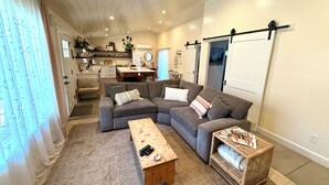 A living room with a sectional sofa, a wooden coffee table, and a wicker side table. - Cottage with gated driveway near downtown & river (Grants Pass)