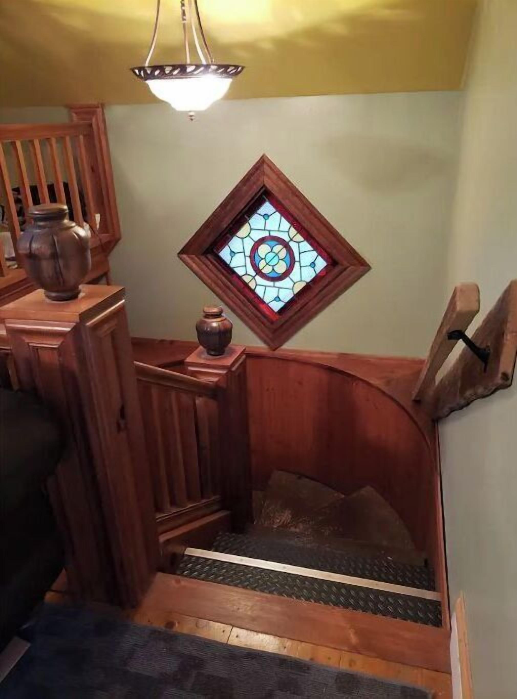 A wooden staircase with a stained glass window at the top.
