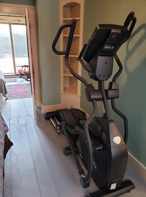 A stationary bike in a room with a sliding glass door leading to a balcony.