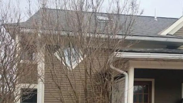 Eine Holzterrasse mit weißer Geländer, eine überdachte Veranda und eine Garagentür.
