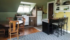 Eine kompakte Küche mit Essbereich, Holzkstühlen, einer kleinen Kochinsel und einem Deckenventilator.