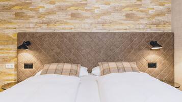 Een bed met een gewatteerd hoofdbord, twee bedlampjes en een muur met een baksteenmotief.
