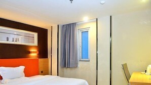 A hotel room with a bed, a desk, a window with curtains, and a wall-mounted picture. - 7days Premium Shenzhen Buji Changlong Metro Station Branch (Shenzhen)