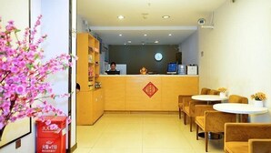 A hotel reception area with a wooden counter, a clock, and a small shrine. There are chairs and tables for guests. - 7days Premium Shenzhen Buji Changlong Metro Station Branch (Shenzhen)