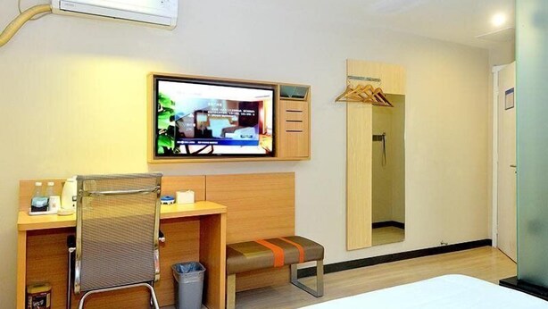 A hotel room with a bed, a desk with a chair, a TV mounted on the wall, a mirror, and a shower area. - 7days Premium Shenzhen Buji Changlong Metro Station Branch (Shenzhen)