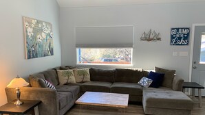 Un salon moderne avec un canapé d’angle, une table basse et une table d’appoint sur laquelle se trouve une lampe.