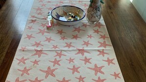 Une table recouverte d’une nappe sur le thème de la « PLAGE », avec un saladier et un objet décoratif.
