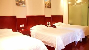 A hotel room with three single beds, wooden headboards, and a large mirror on the wall.