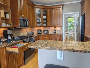 A kitchen with wooden cabinets, granite countertops, a microwave, a stove, and a refrigerator. - Edgewater Escape - Your ultimate lakefront retreat for unforgettable family fun and relaxation (Mooresville)