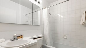 Ein modernes Badezimmer mit Waschbecken, Toilette und Badewanne, alles in Weiß.