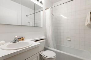 Un bagno moderno con lavandino, vaso e vasca da bagno bianchi.