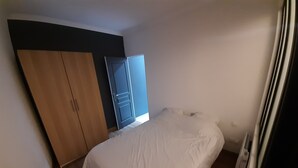 A bedroom with a bed, a wardrobe, and a door. - 2-room apartment, near RER, bus and castle (Rambouillet)