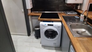 A compact kitchen with a built-in washer, a sink, and a stove. - 2-room apartment, near RER, bus and castle (Rambouillet)