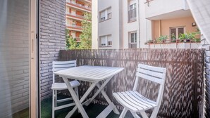 A balcony with a white table and chairs, a brick wall, and a wooden fence.