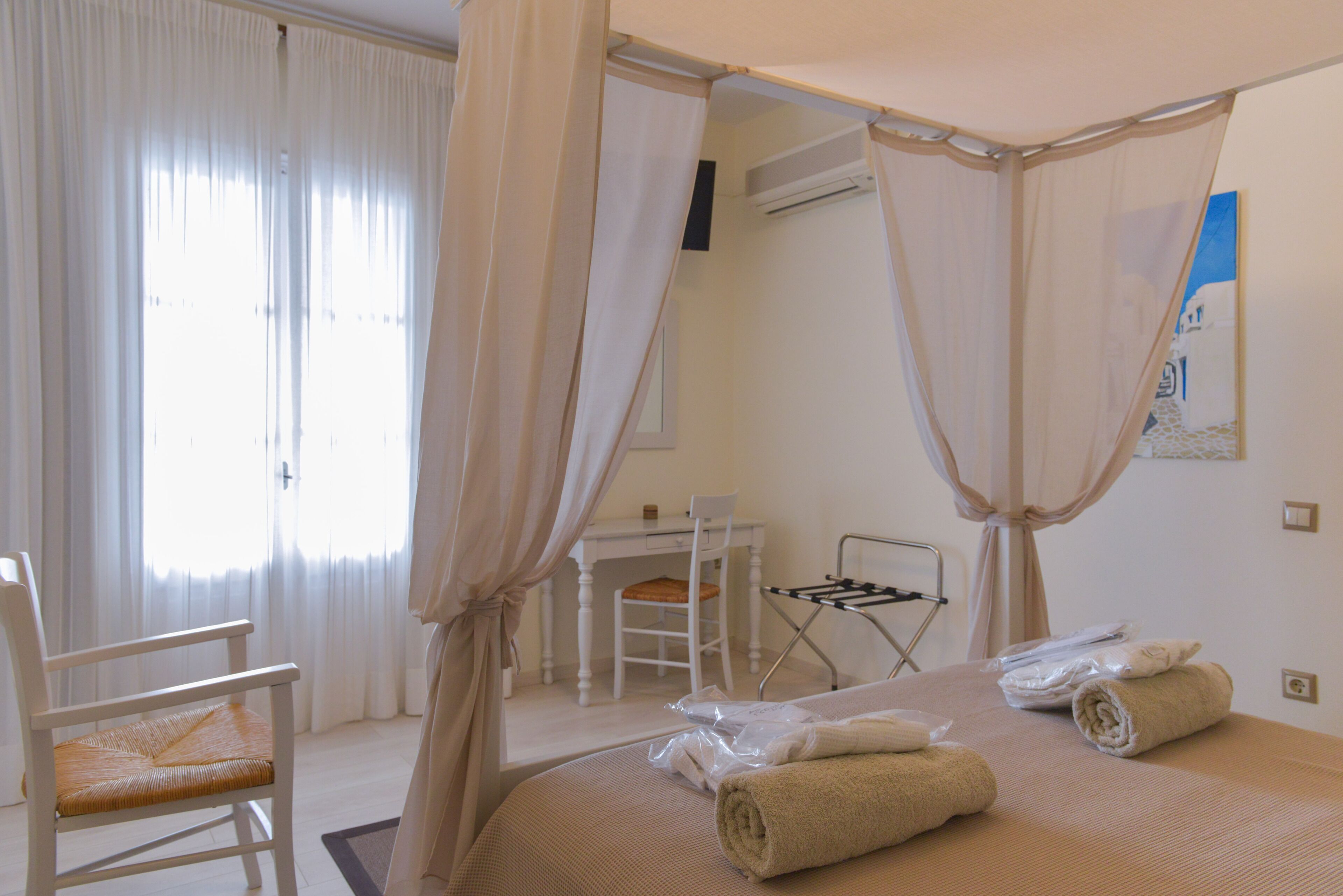 Ein Hotelzimmer mit Bett, Stuhl, Schreibtisch und einem Fenster mit Vorhängen.