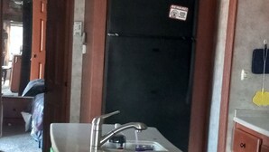 Uma cozinha com ilha integrada, geladeira preta e armários de madeira.