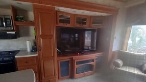 Um espaço compacto para viver, com cozinha compacta, televisão e sofá.