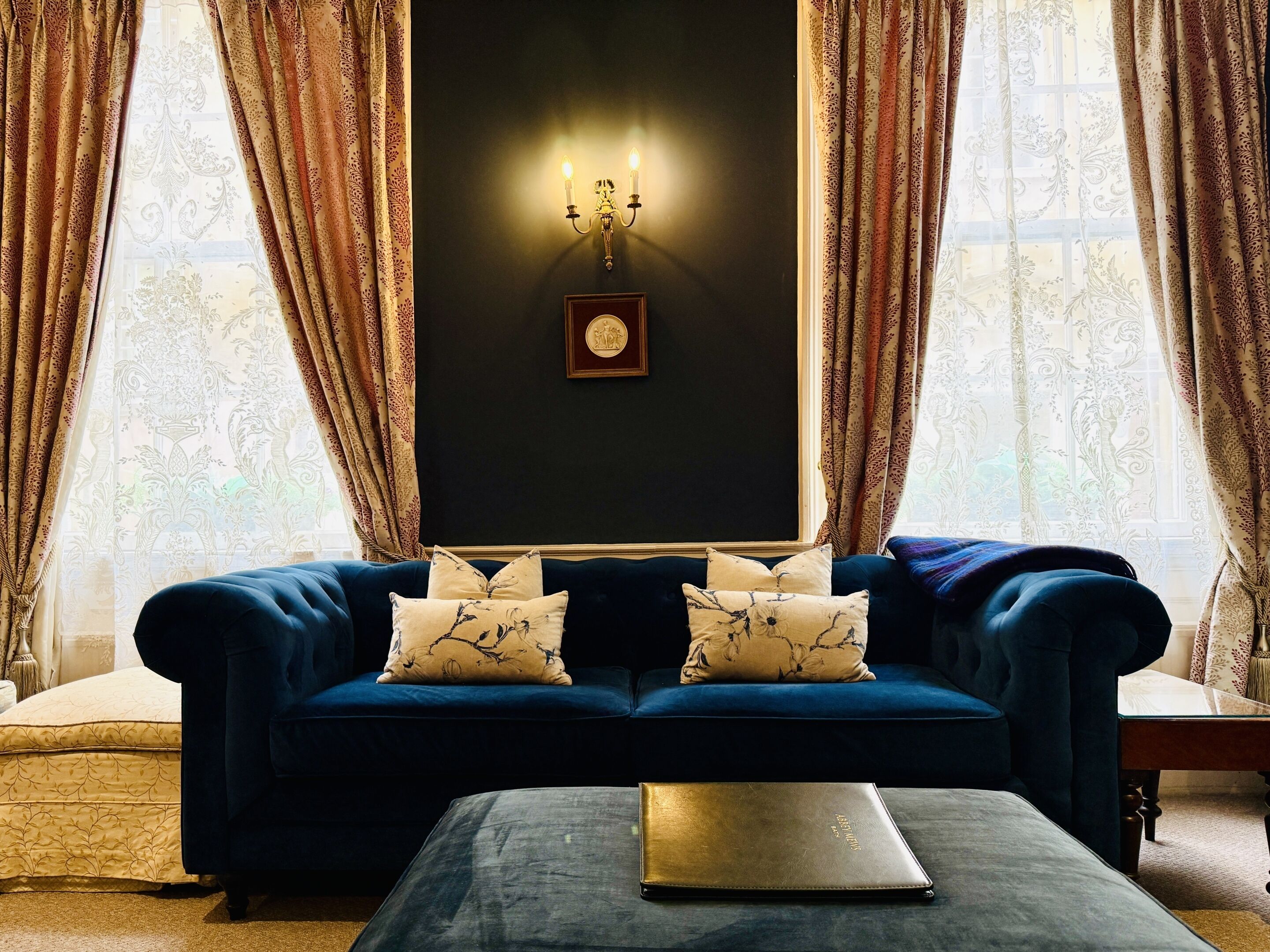 Un sofá azul oscuro con cojines estampados, un cuadro en la pared y una mesa con un ordenador portátil.
