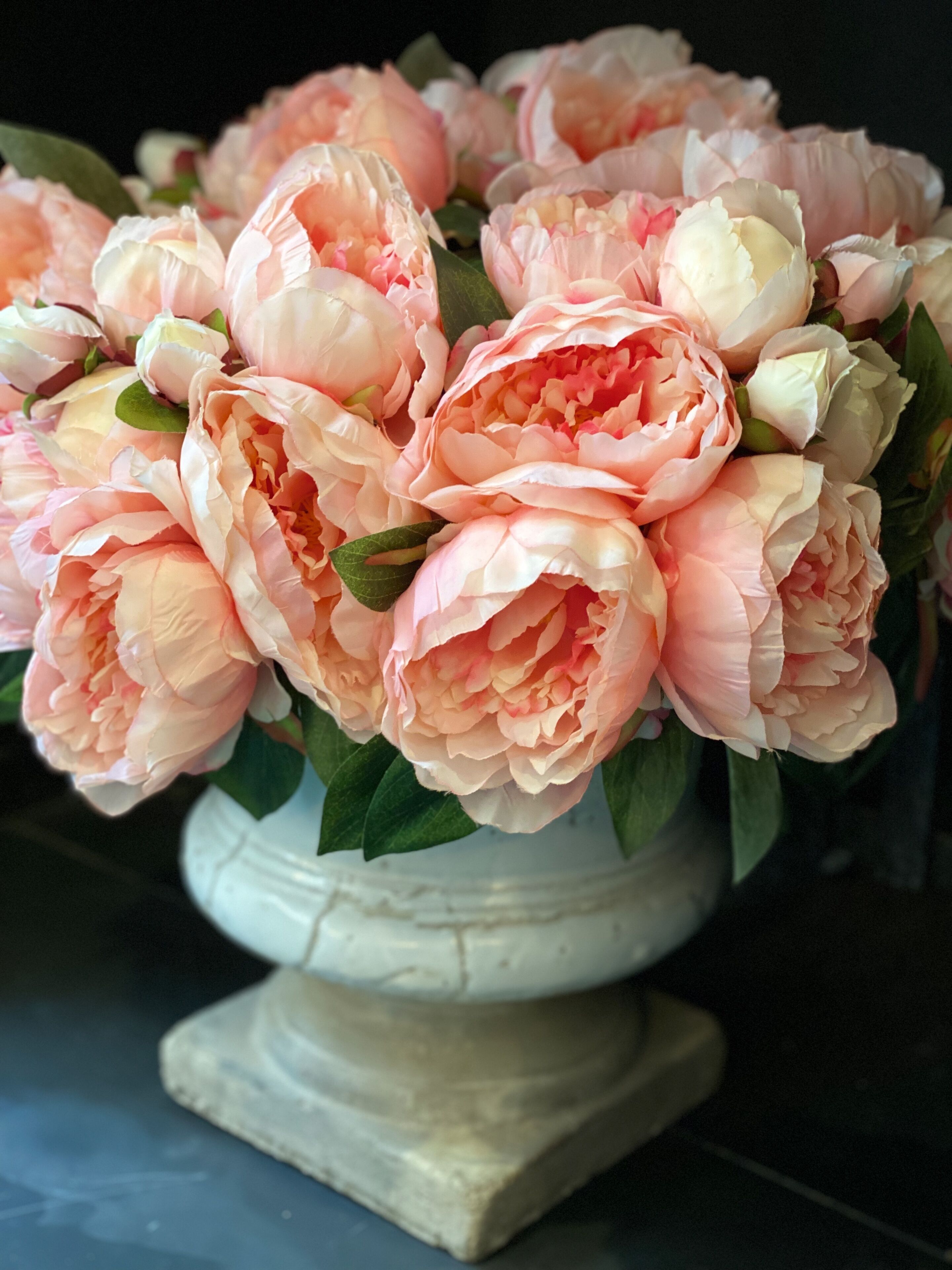 A bouquet of peonies in a white vase.