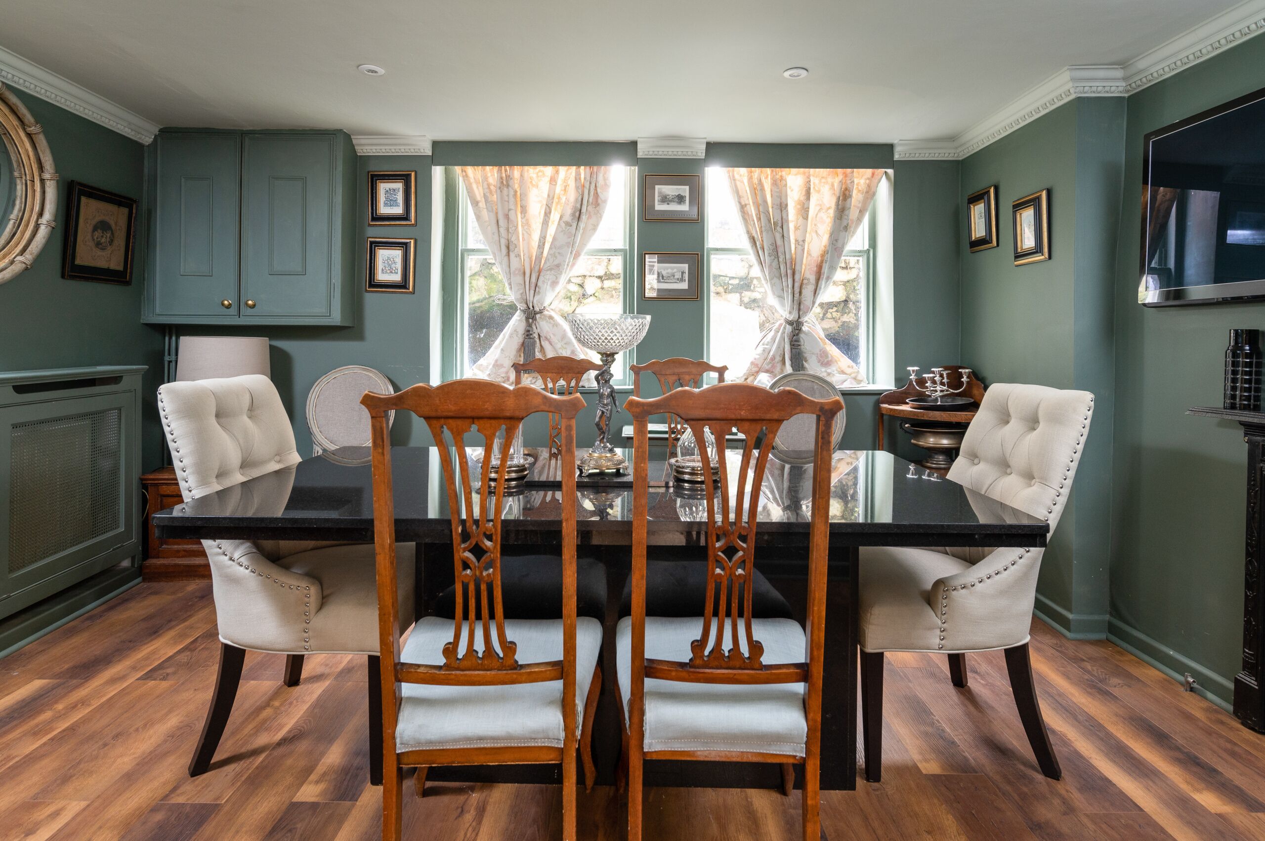 A dining area with a black table, four wooden chairs, and a chandelier.