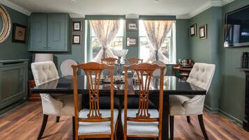 A dining area with a black table, four wooden chairs, and a chandelier.
