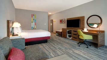 A hotel room with a bed, a desk, a chair, a TV, and a mirror.