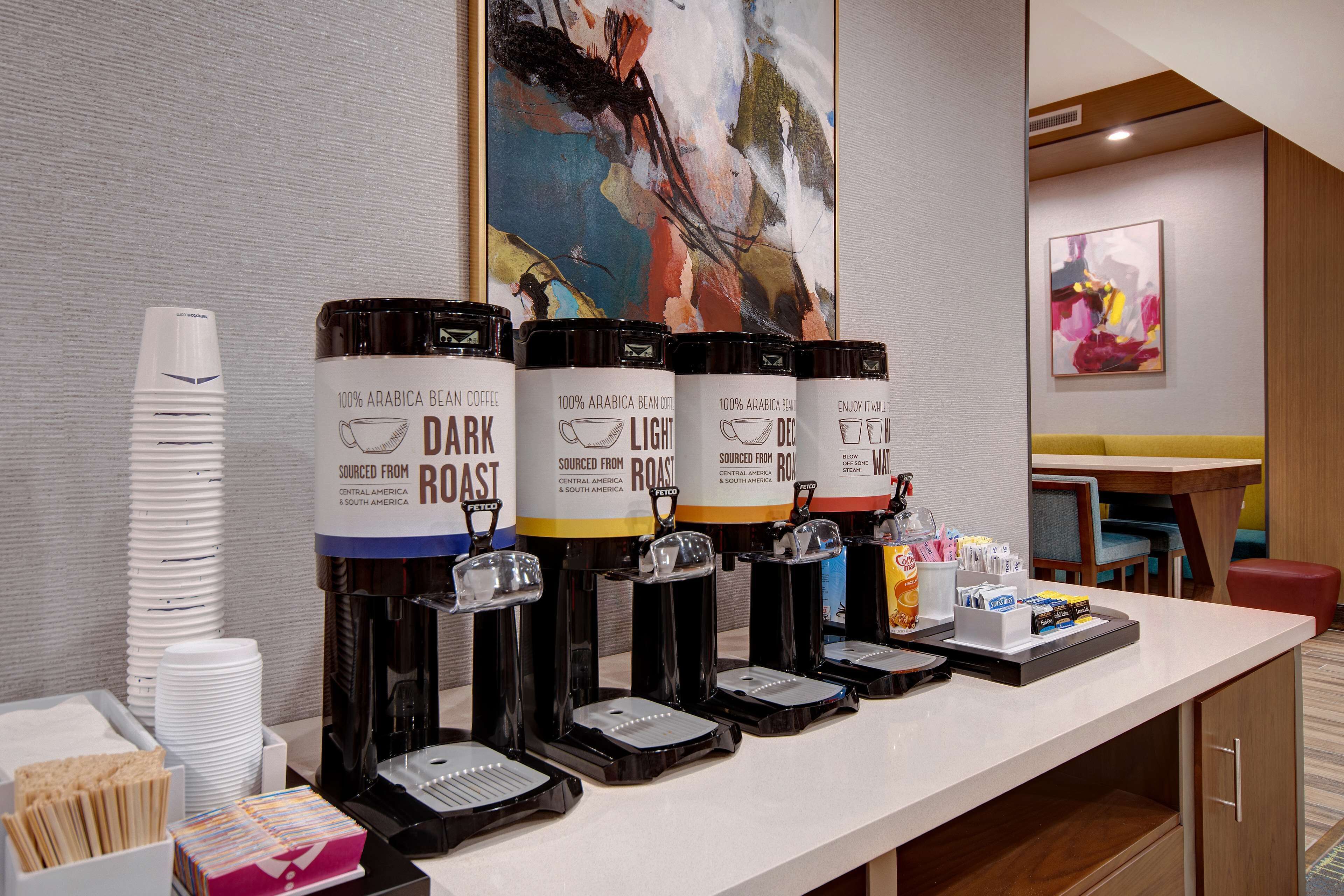 A coffee station with four coffee dispensers labeled 'Dark Roast,' 'Light Roast,' and 'Decaf,' sourced from Central and South America.