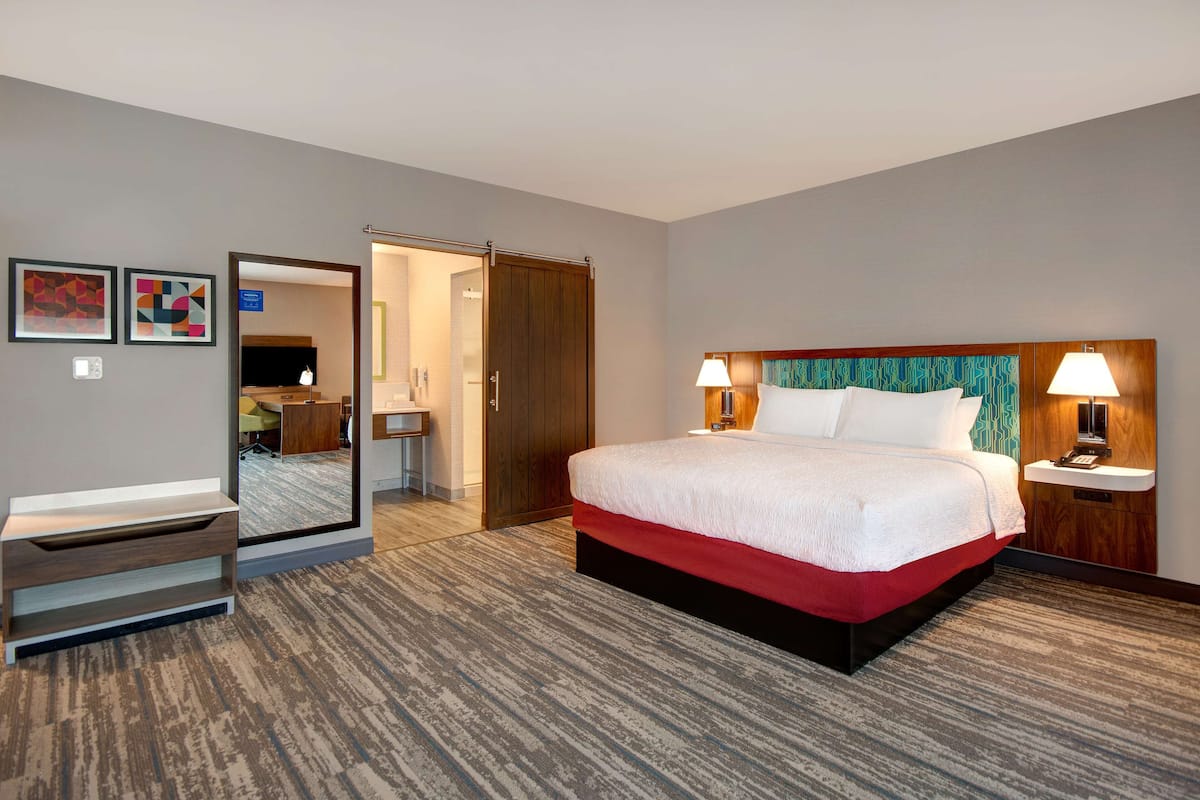A hotel room with a bed, bedside tables, a mirror, a desk, and a wardrobe.