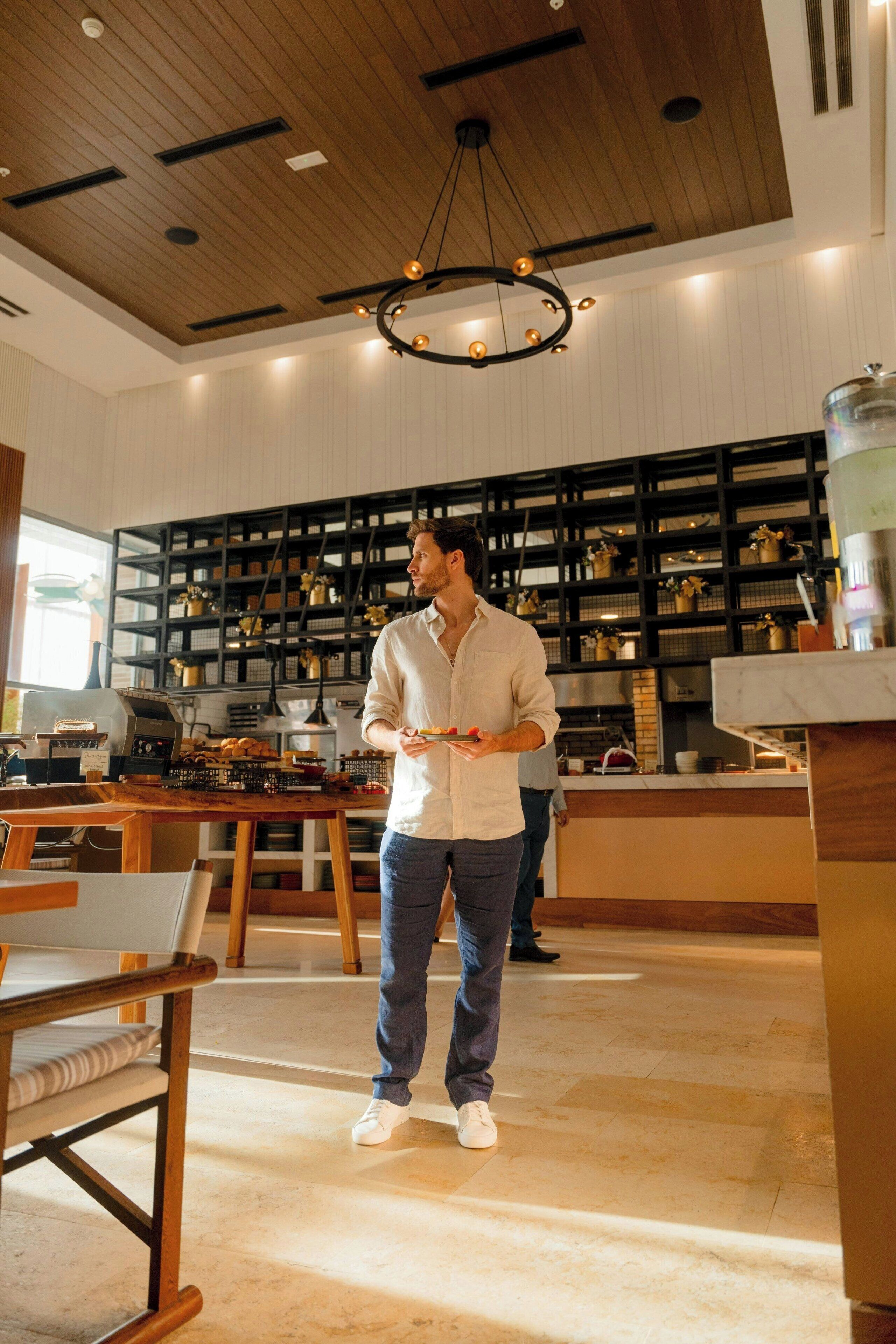 Una cocina moderna con techo de madera, estanterías negras y un candelabro central.