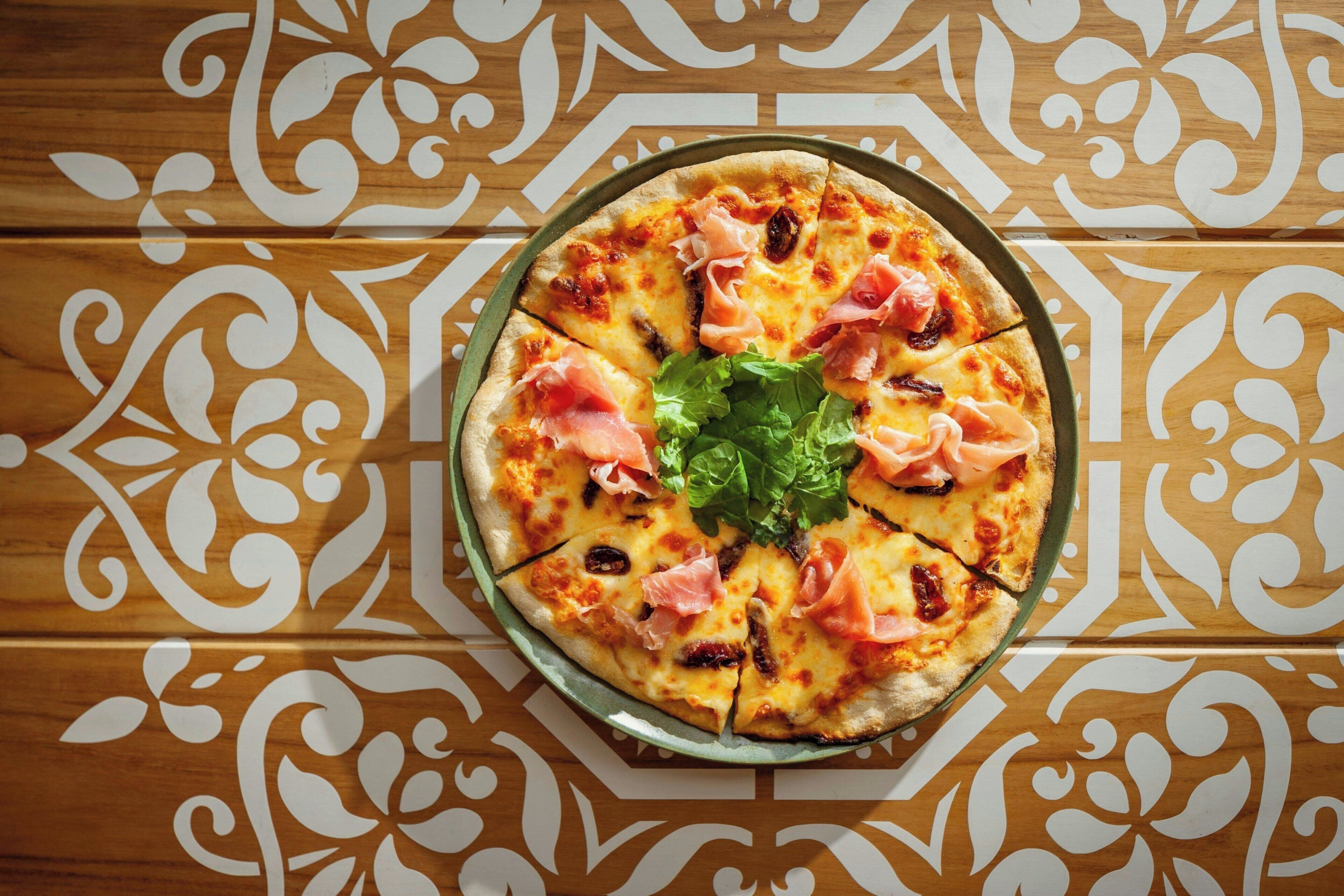 Una pizza sobre un plato con un mantel de madera decorativo.