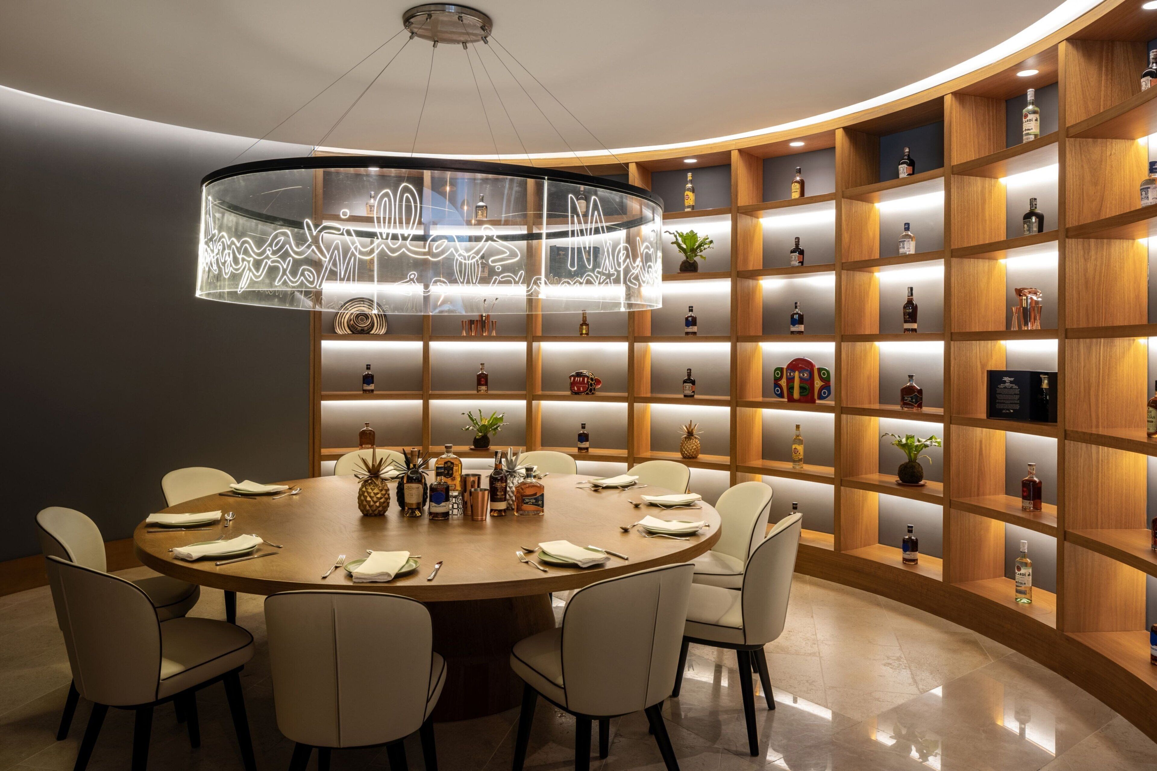 Un comedor moderno con una mesa redonda, seis sillas y una lámpara de cristal.